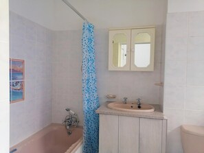 Un baño con bañera, cortina de ducha, lavamanos y espejo.