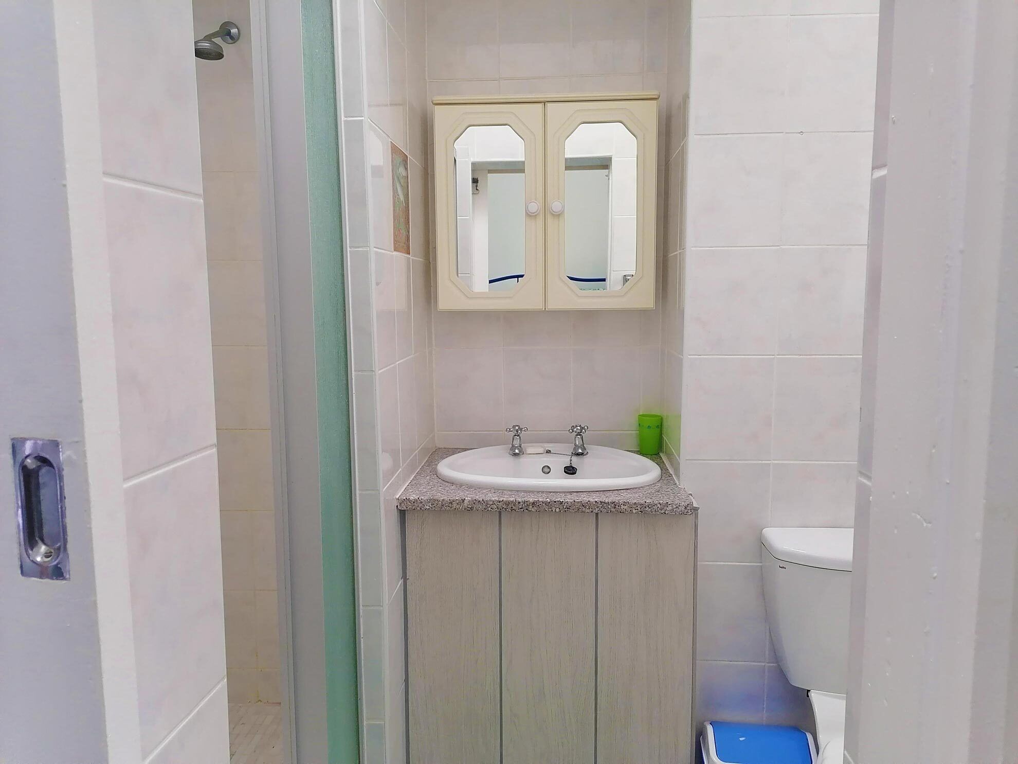 A bathroom with a white sink, two mirrors, and a toilet.