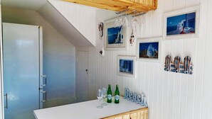 A kitchen with wooden cabinets, a white countertop, and a door leading to another room. - Claridges 104 (Margate)