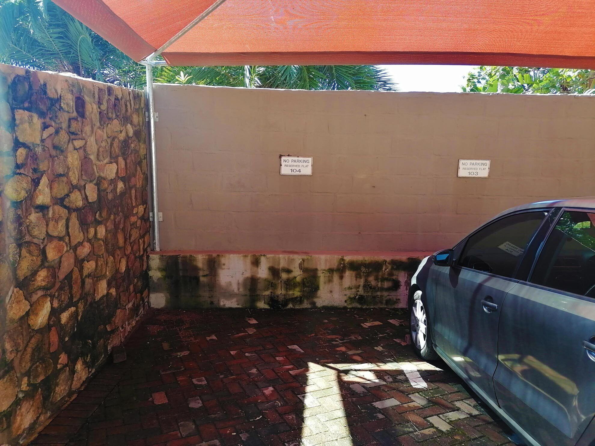 A parking area with a stone wall and two 'No Parking' signs.