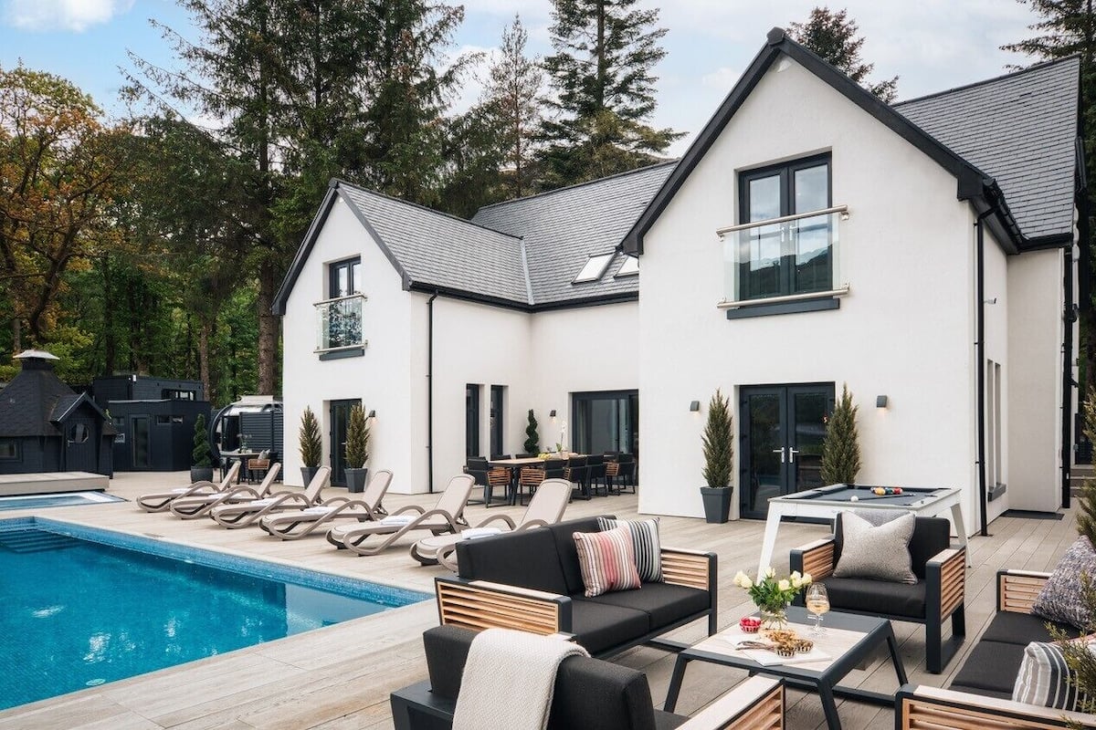 A modern house with a pool, outdoor seating, and a dining area.