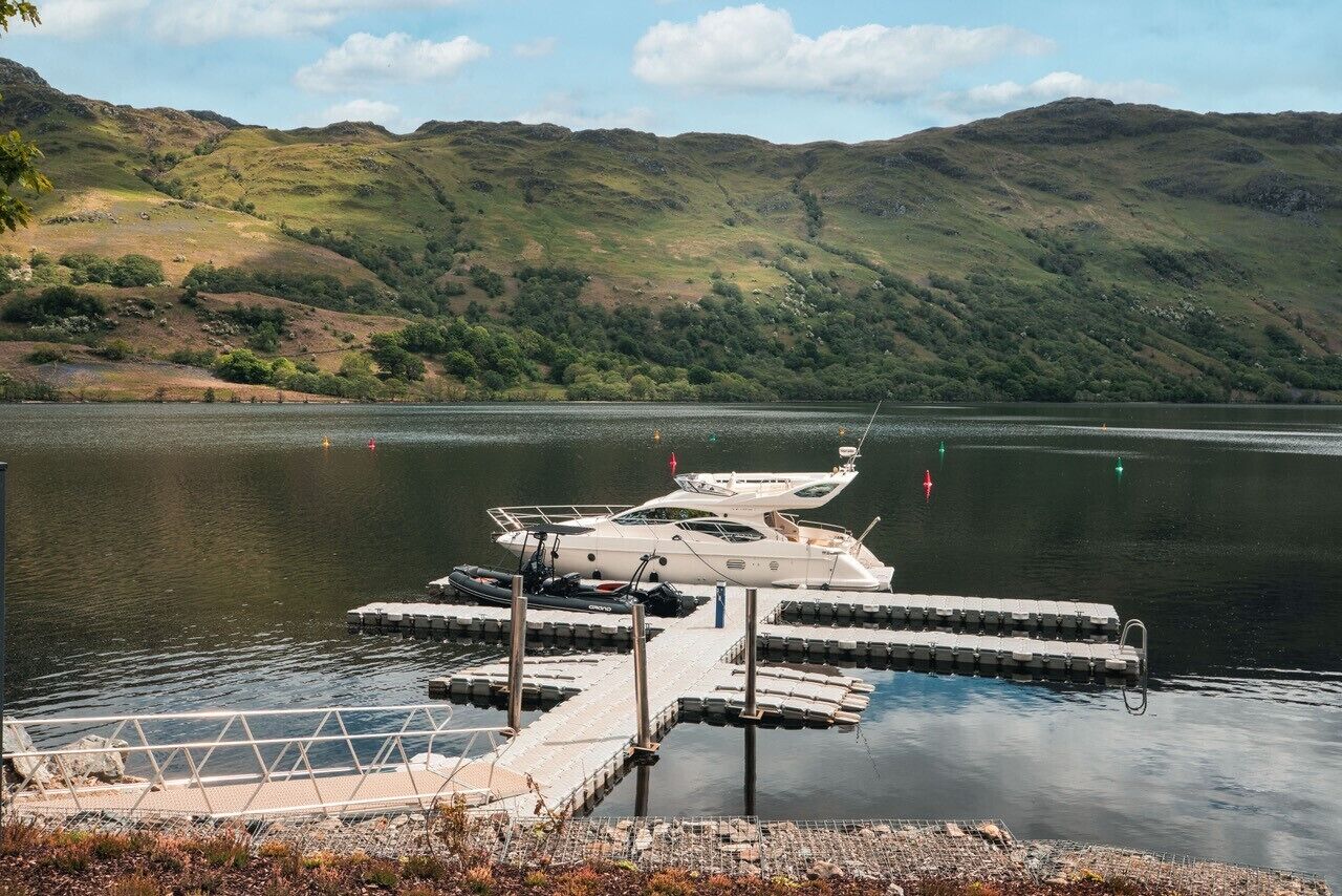 A dock with a boat moored at a lake surrounded by hills.