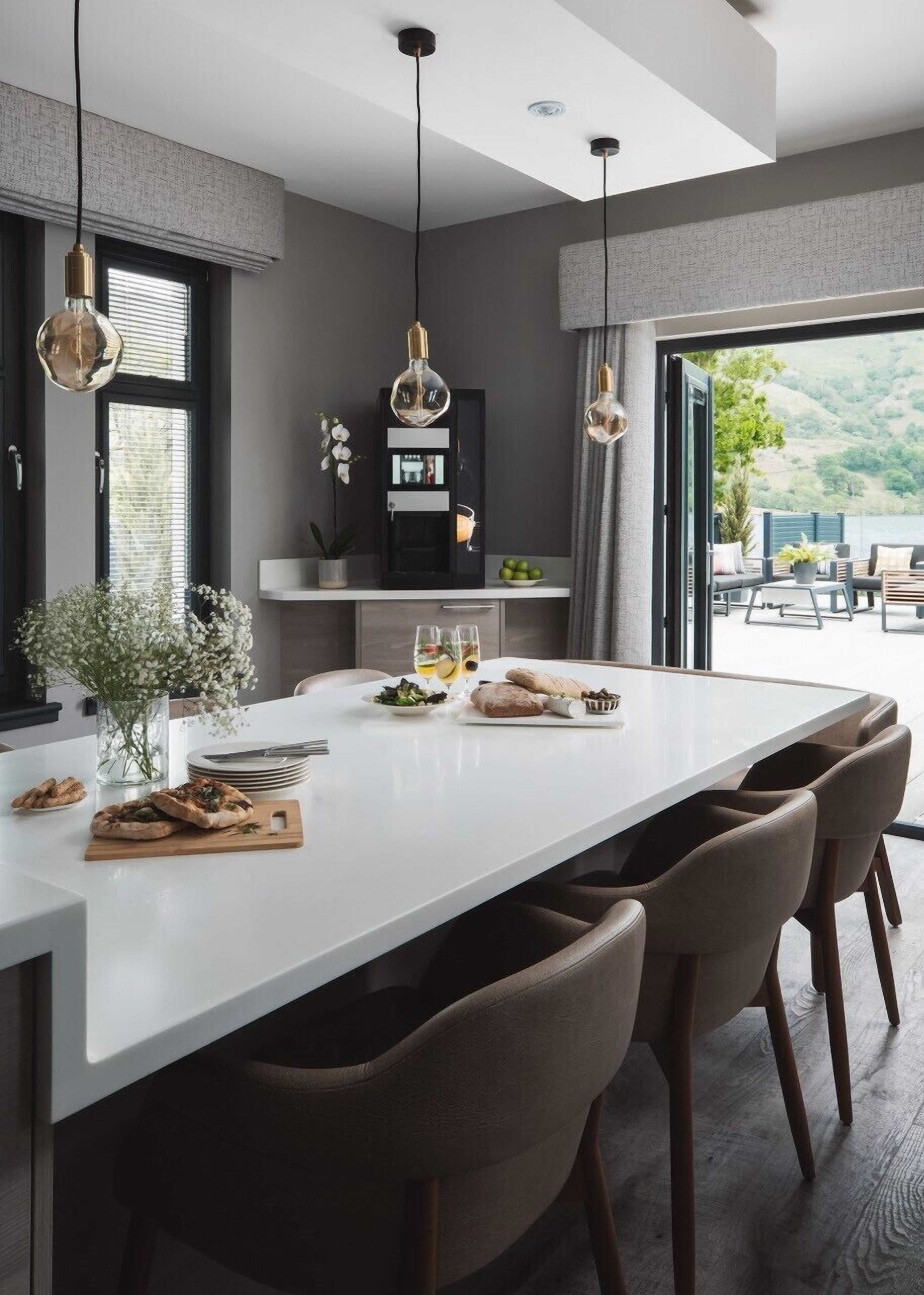 A modern kitchen with a central island, pendant lighting, and a view of the outdoors.