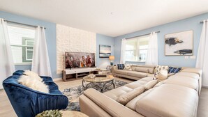 Un salon décoré dans des tons de bleu et de blanc, avec un canapé, un fauteuil, une table basse et des œuvres d’art accrochées aux murs.