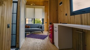 A compact room with a wooden ceiling, a bed with a checkered bedspread, a small desk, and a window. - Arsuz Bungalov (Arsuz)