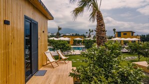 A wooden building with a pool area, including lounge chairs and umbrellas. - Arsuz Bungalov (Arsuz)