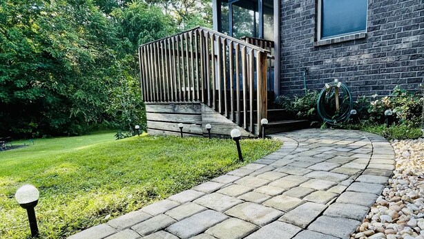 A stone pathway leading to a house with a wooden fence and a garden. - Lovely Guest Apartment<br> (Pace)