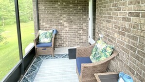 A covered porch with wicker furniture, a ceiling fan, and a view of a grassy area. - Lovely Guest Apartment<br> (Pace)