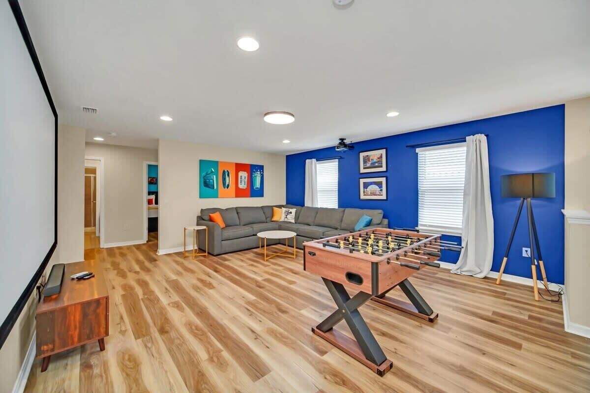 A living room with a foosball table, a gray sofa, and a coffee table.