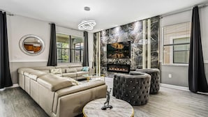 Een moderne woonkamer met een hoekbank, een open haard, een televisie en een accentmuur van marmer.