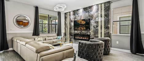 A modern living room with a sectional sofa, a fireplace, a TV, and a marble accent wall.
