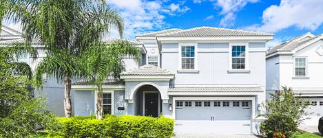 A two-story house with a garage, a front entrance, and a well-maintained lawn.