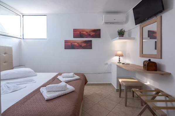 A hotel room with a bed, a desk, a chair, a TV, and two paintings on the wall. - Family Apartment with terrace and sea view 10 minutes from the beach (Κίσσαμος)