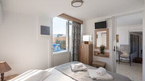 Habitación de hotel con cama, escritorio, silla, televisor y ventana con vistas al exterior.