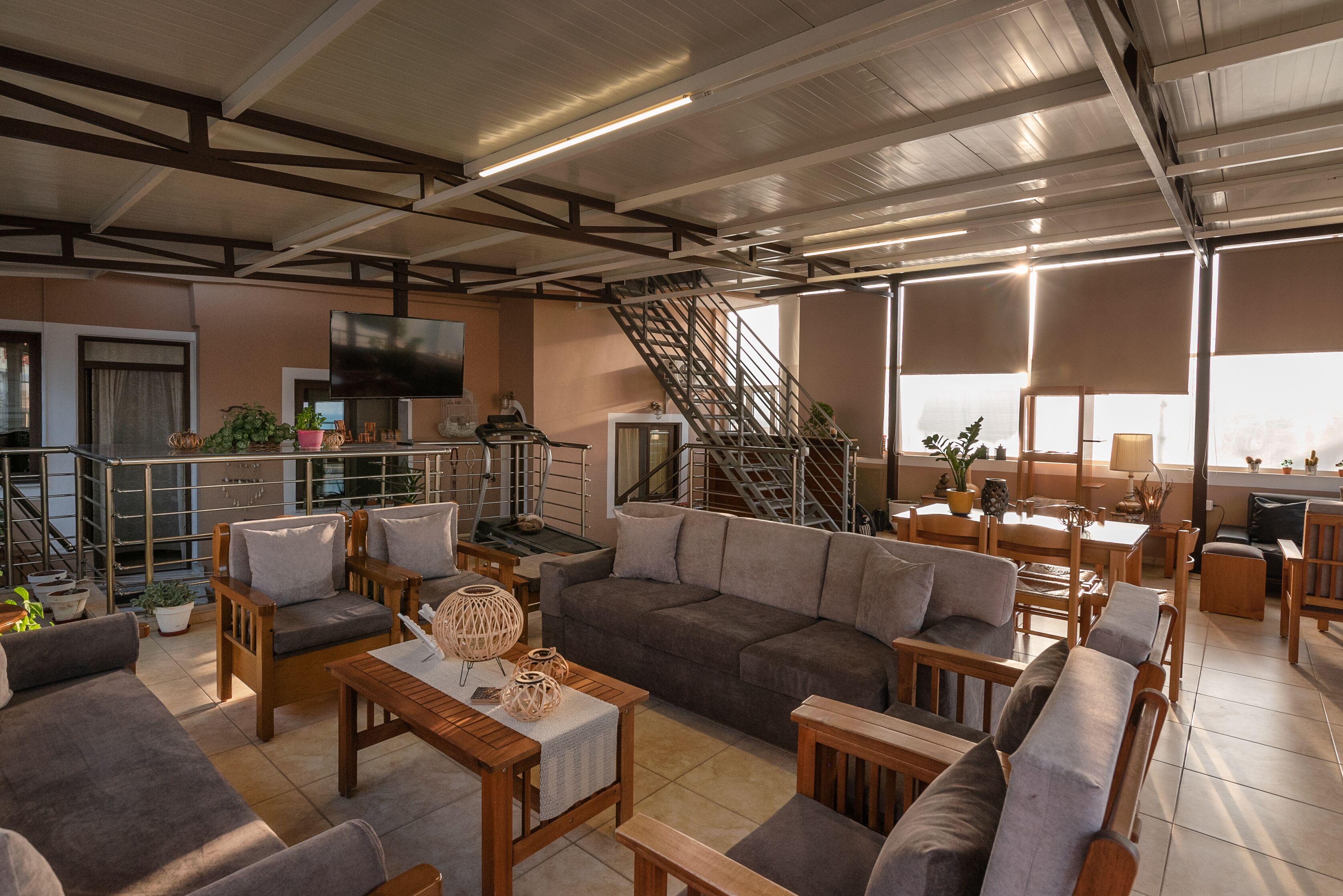 A spacious living area with a sofa set, wooden tables, and a staircase leading to an upper level.