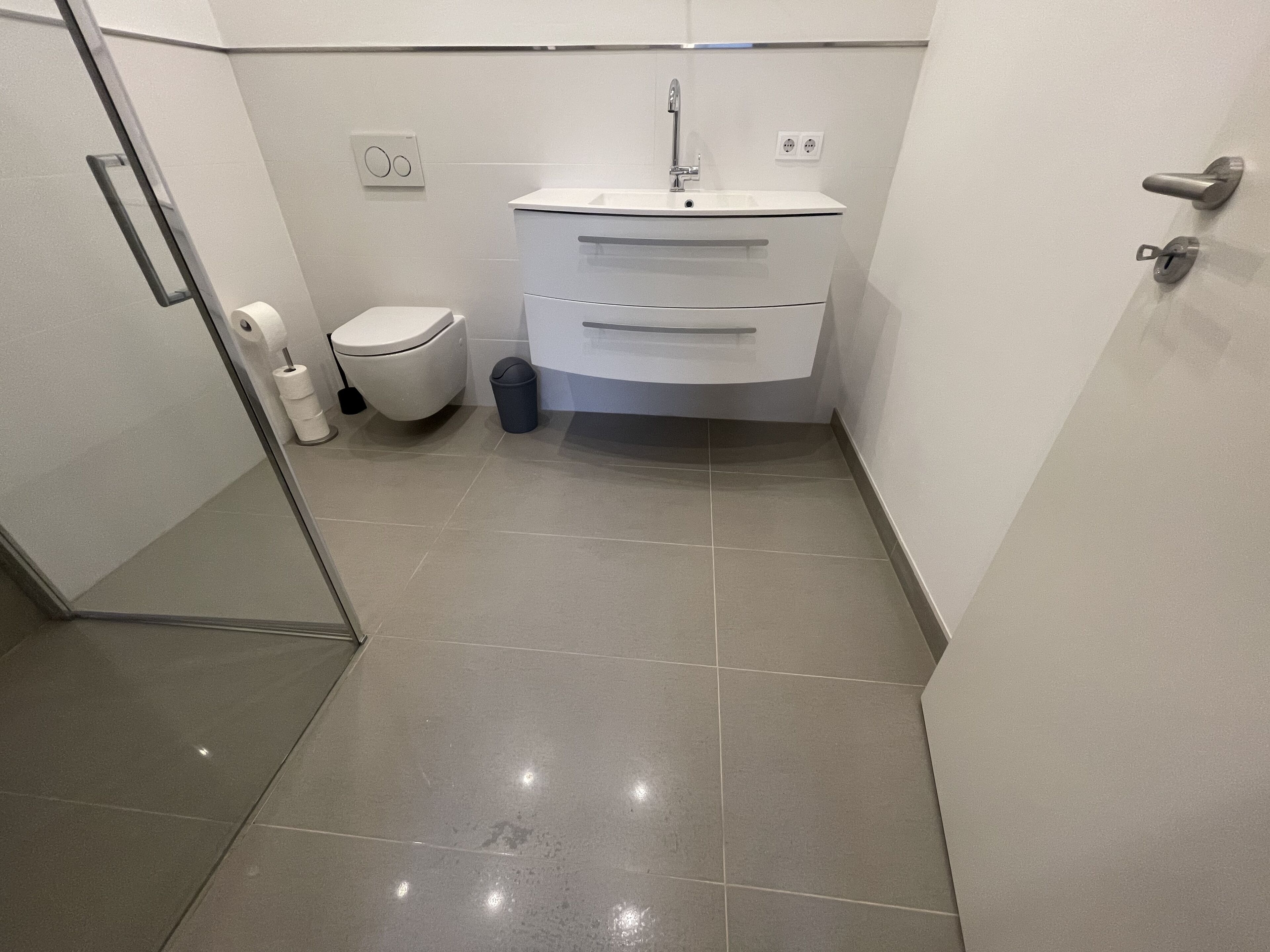 A modern bathroom with a toilet, sink, and shower.