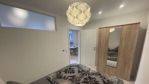 Une chambre à coucher comprenant un lit, une armoire et une porte donnant sur une autre pièce.