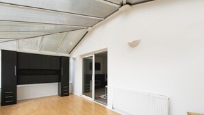 Un'ampia stanza con soffitto a falde, un armadio nero incassato, una porta a vetri scorrevoli che dà su un balcone e un termosifone bianco.