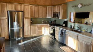 A modern kitchen with wooden cabinets, stainless steel appliances, and a tiled floor. - Cute, cozy, updated cabin in the pines (Pinetop)