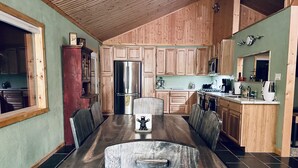 A spacious kitchen with wooden cabinets, a stainless steel refrigerator, and a dining area with a marble table and chairs. - Cute, cozy, updated cabin in the pines (Pinetop)