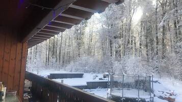 Una terraza de madera con vista a un bosque nevado.
