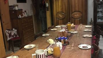 A long wooden dining table set with plates, glasses, and a pitcher of juice.