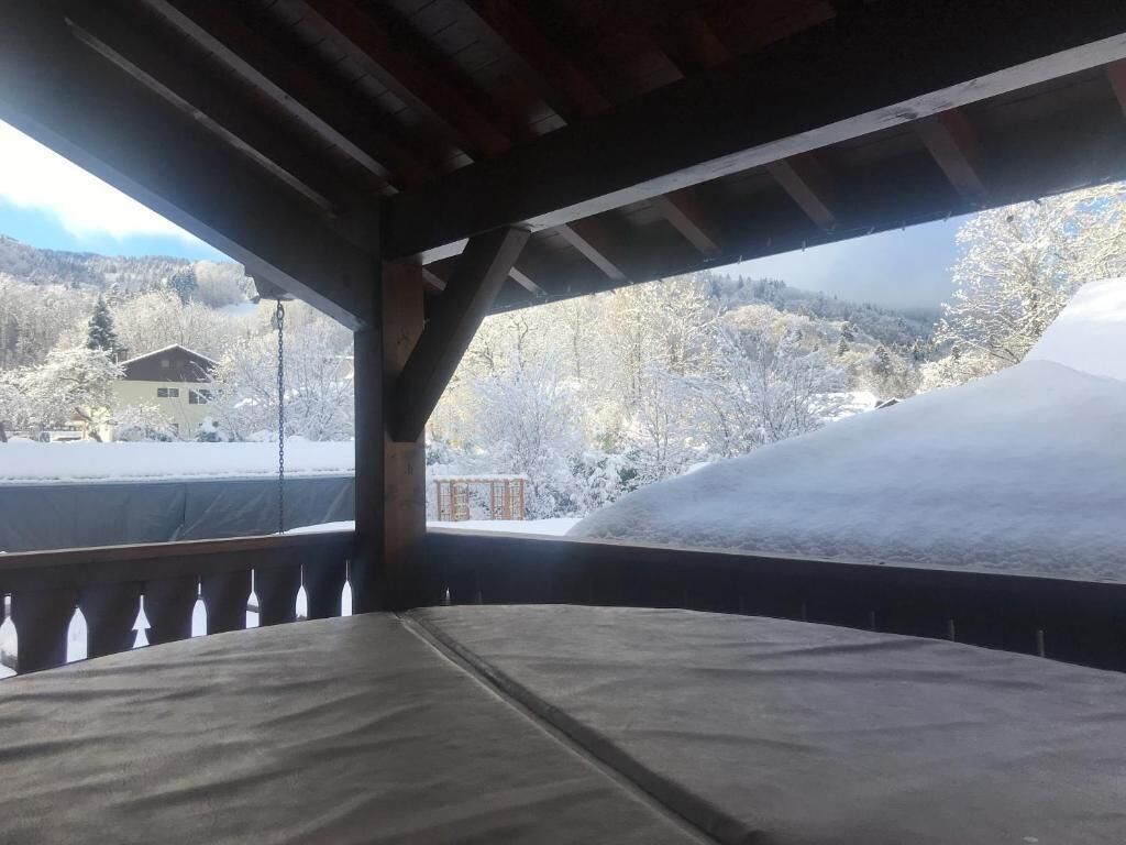 A covered outdoor area with a view of a snowy landscape and a building in the background.