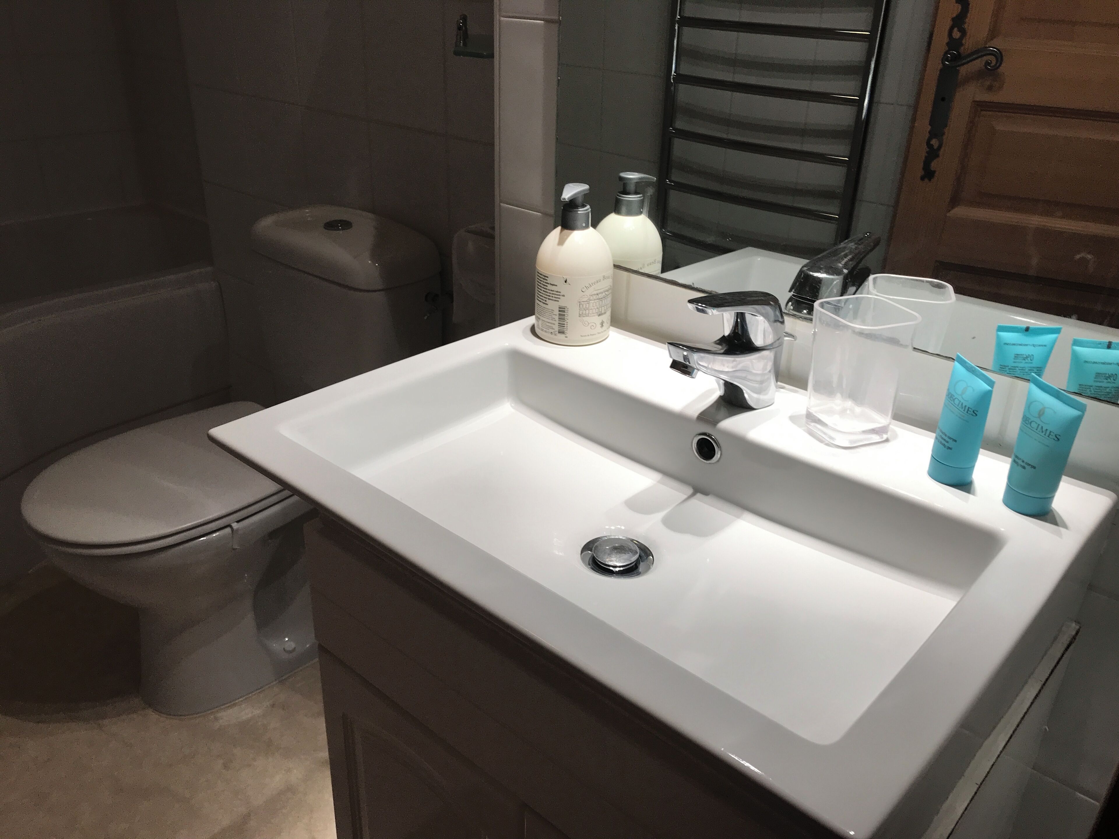A bathroom with a white sink, a mirror, and toiletries.