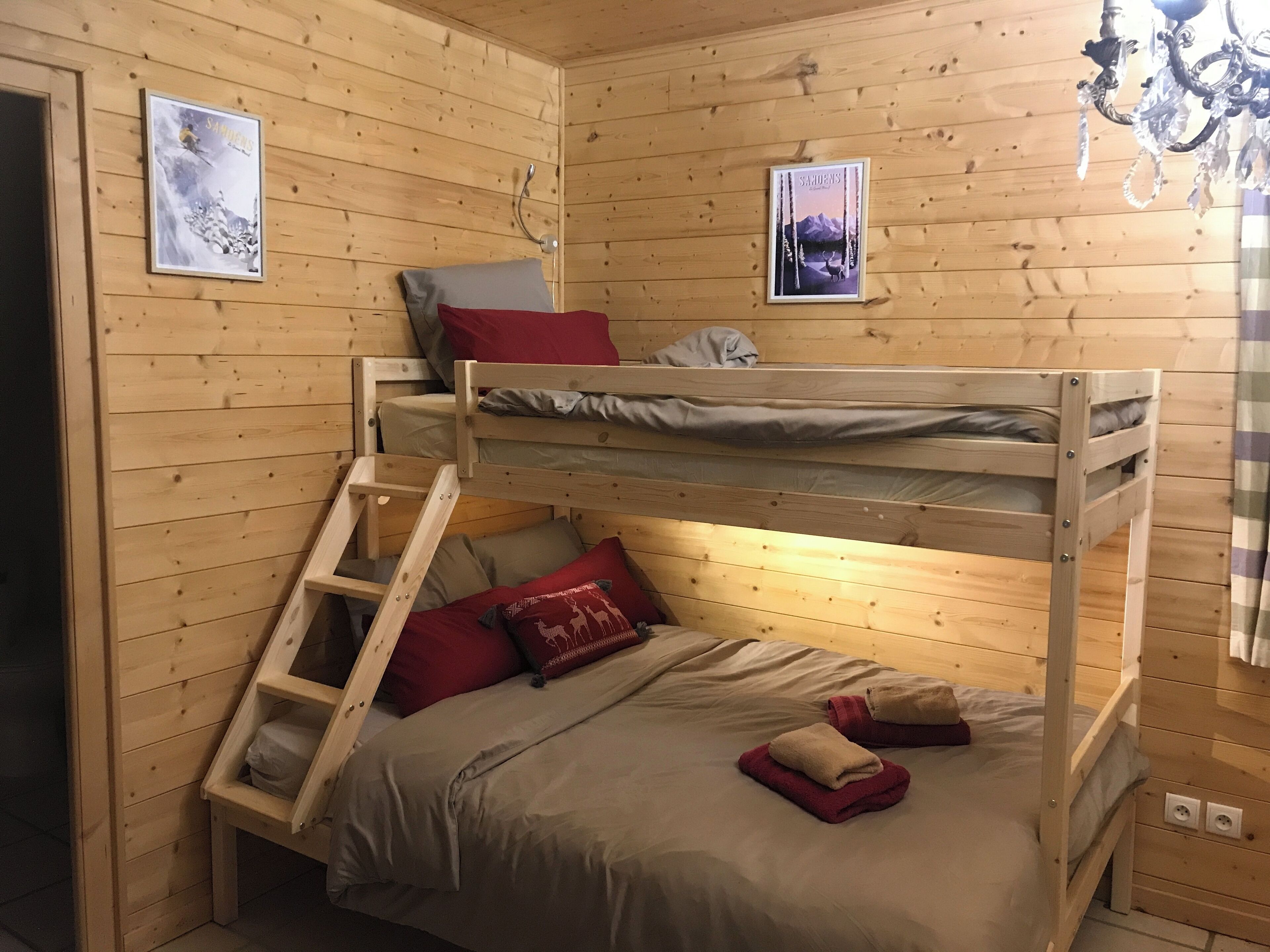A bunk bed room with wooden walls, a ladder, and two framed pictures.