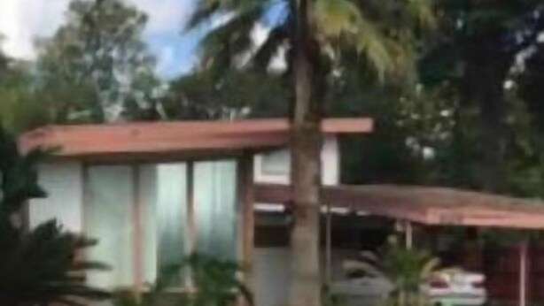 Una casa moderna con un gran ventanal, techo rojo y césped cuidado.