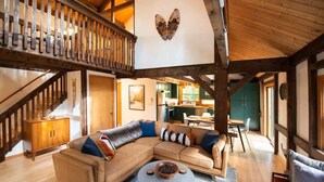 A spacious living area with a large L-shaped sofa, a round coffee table, and a wooden staircase. - Stonebridge Cabin: Modern Amenities, Enjoy Nature! (Lee)