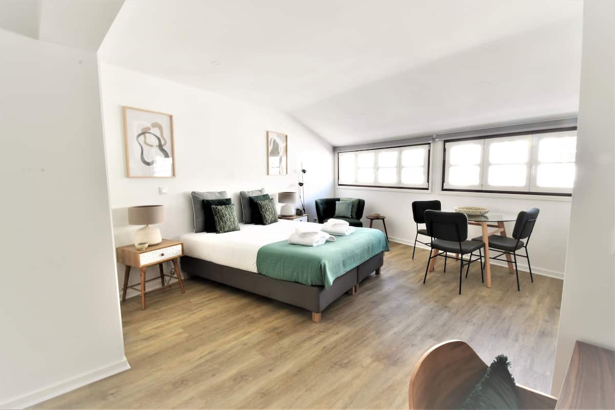 Quarto moderno com uma cama grande, uma escrivaninha e um espaço para refeições.