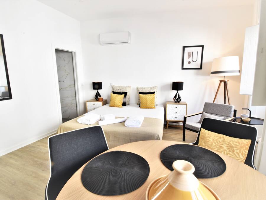A hotel room with a bed, bedside tables, a desk, a chair, and a dining table.