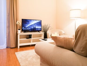 Un salon moderne avec un téléviseur à écran plat, un canapé, une table basse et une lampe.
