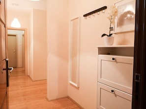 A hallway with wooden flooring, a white door, and a white cabinet with drawers.