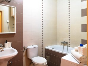 Une salle de bain équipée d’un lavabo, de toilettes, d’une baignoire et d’un miroir.