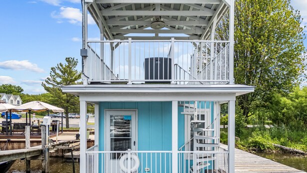 Une péniche amarrée, avec une façade bleue, une rambarde blanche et un escalier menant à une terrasse.