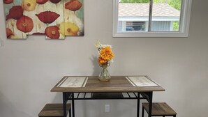 A dining area with a wooden table and bench, a vase with flowers, and a painting on the wall. - Great Place to Relax! (Cleveland)