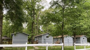 A row of small, single-story cabins with white railings, surrounded by lush greenery and trees. - Great Place to Relax! (Cleveland)