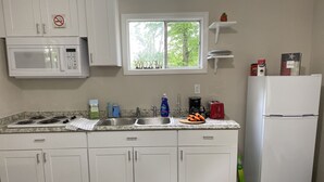 A kitchen with white cabinets, a microwave, a stove, a sink, a window, and a refrigerator. - Great Place to Relax! (Cleveland)