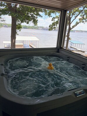 Un bain à remous avec un canard, une vue sur un lac et une jetée dotée d’un espace de repos abrité.