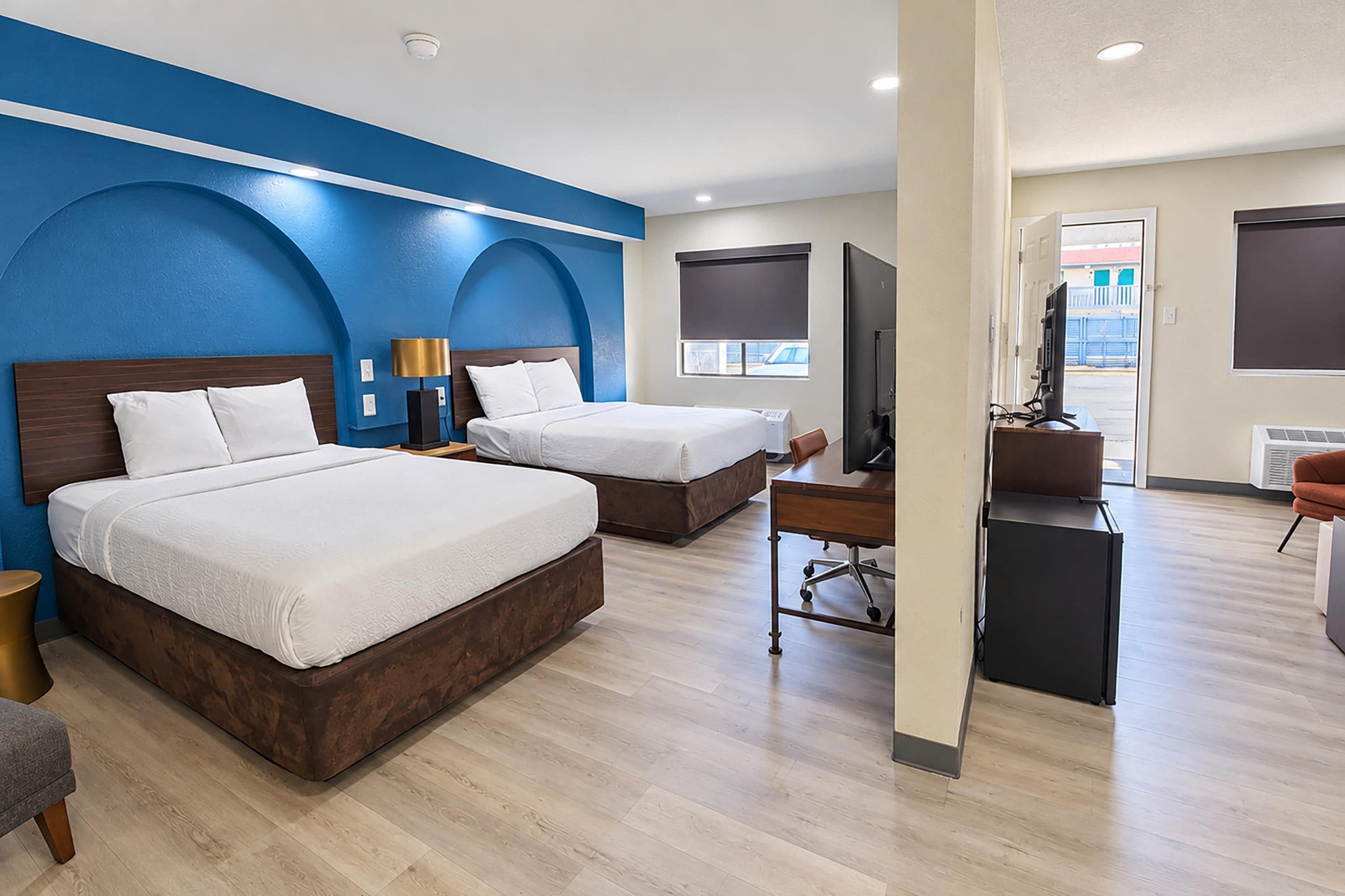 Habitación de hotel con dos camas, un escritorio, un televisor y vistas al exterior.