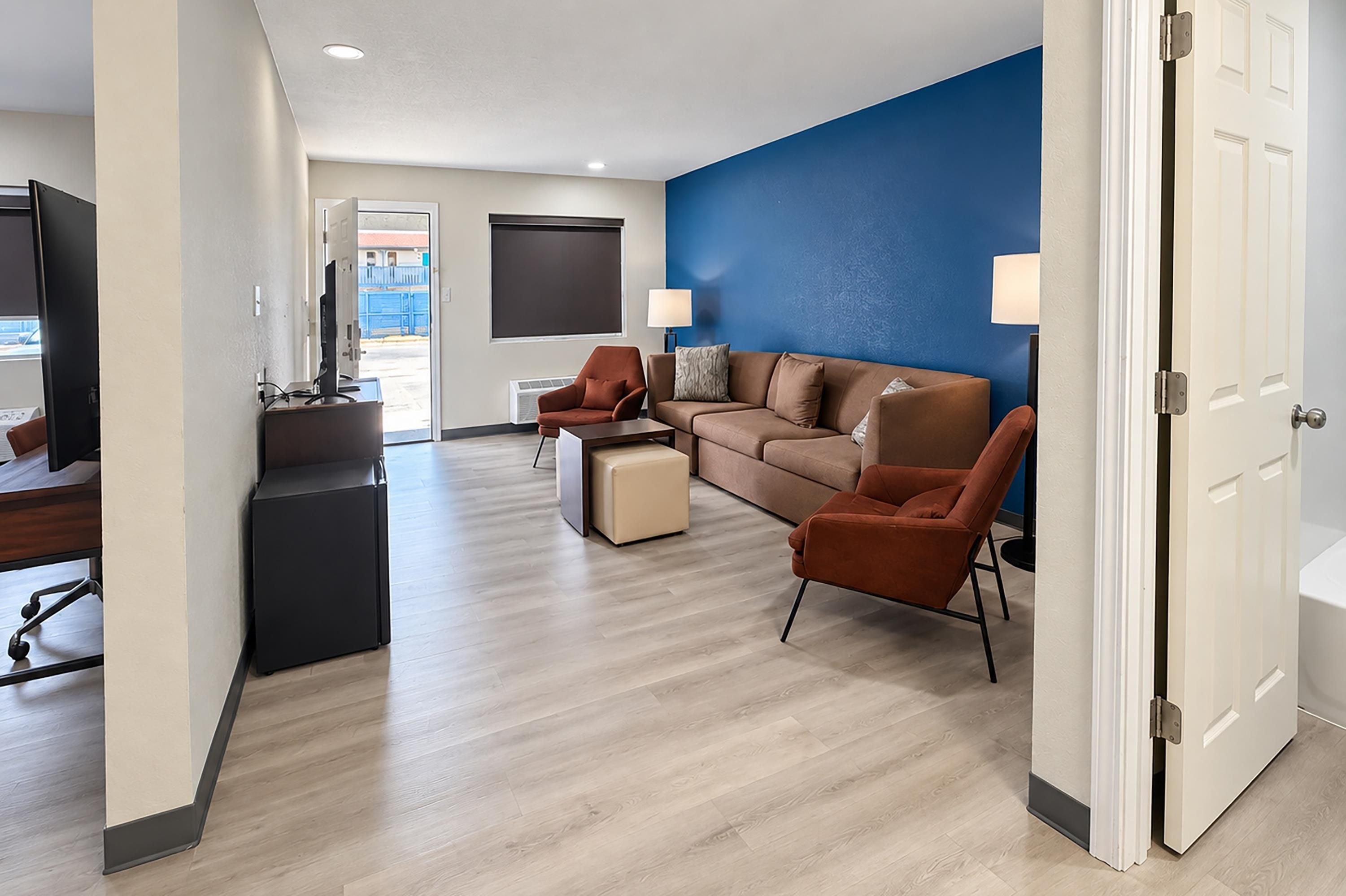 Una habitación de hotel moderna con sofá, sillones, escritorio y televisor.