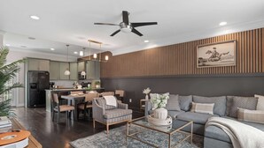 A modern living room with a sofa, coffee table, and a dining area with chairs and a table.