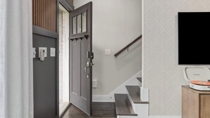 A staircase with a wooden handrail, a door with a window, and a flat-screen TV mounted on the wall.