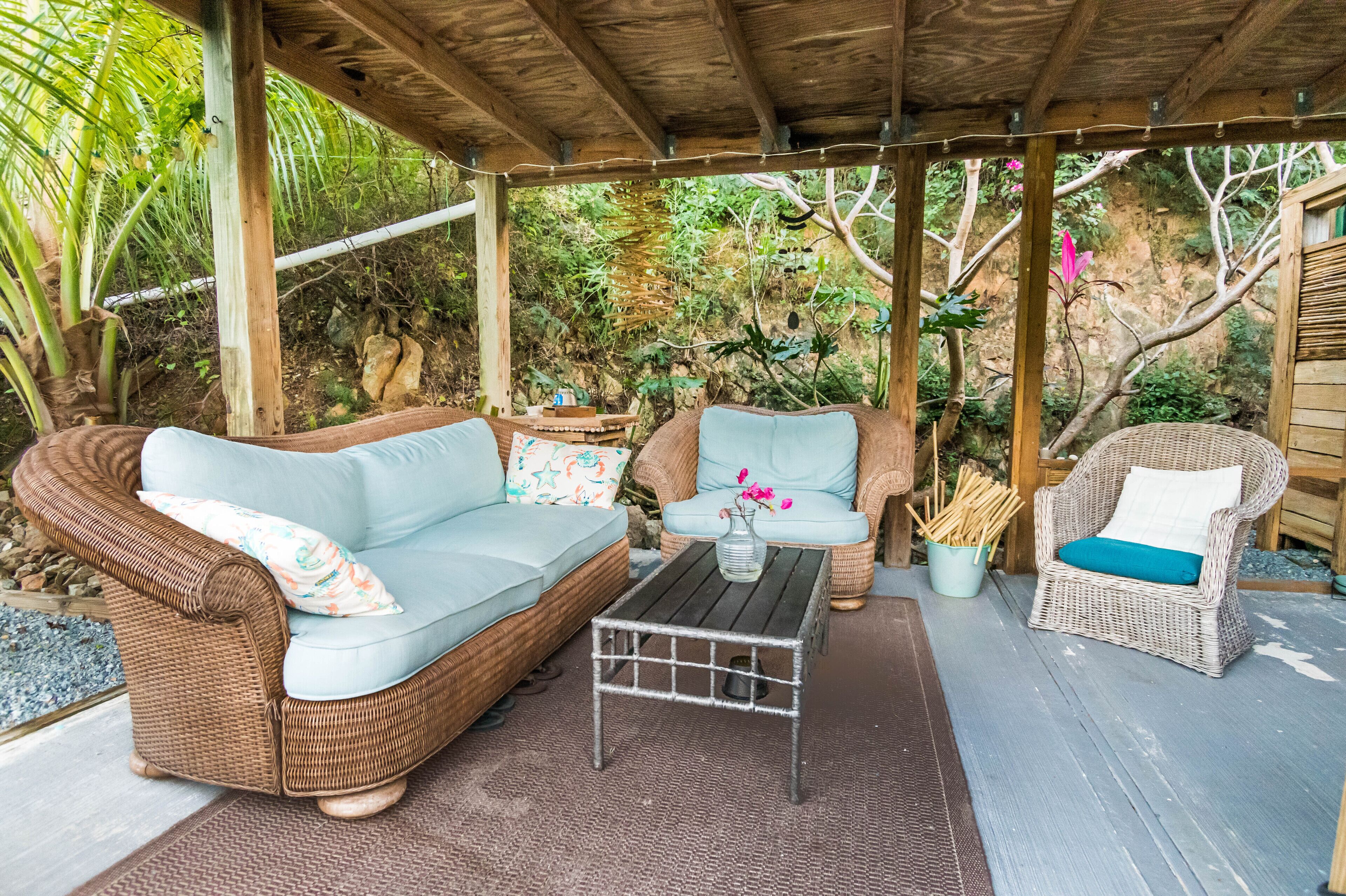A covered outdoor seating area with wicker furniture and a small table.