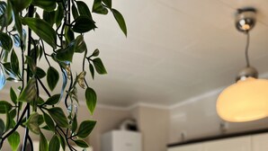 Una cocina moderna con gabinetes blancos, encimera de acero inoxidable y una lámpara colgante.