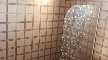 Une douche avec une porte en verre et un mur carrelé.
