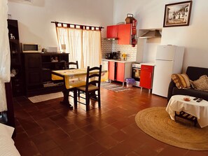 Un espacio habitable compacto con comedor, kitchenette y sofá.