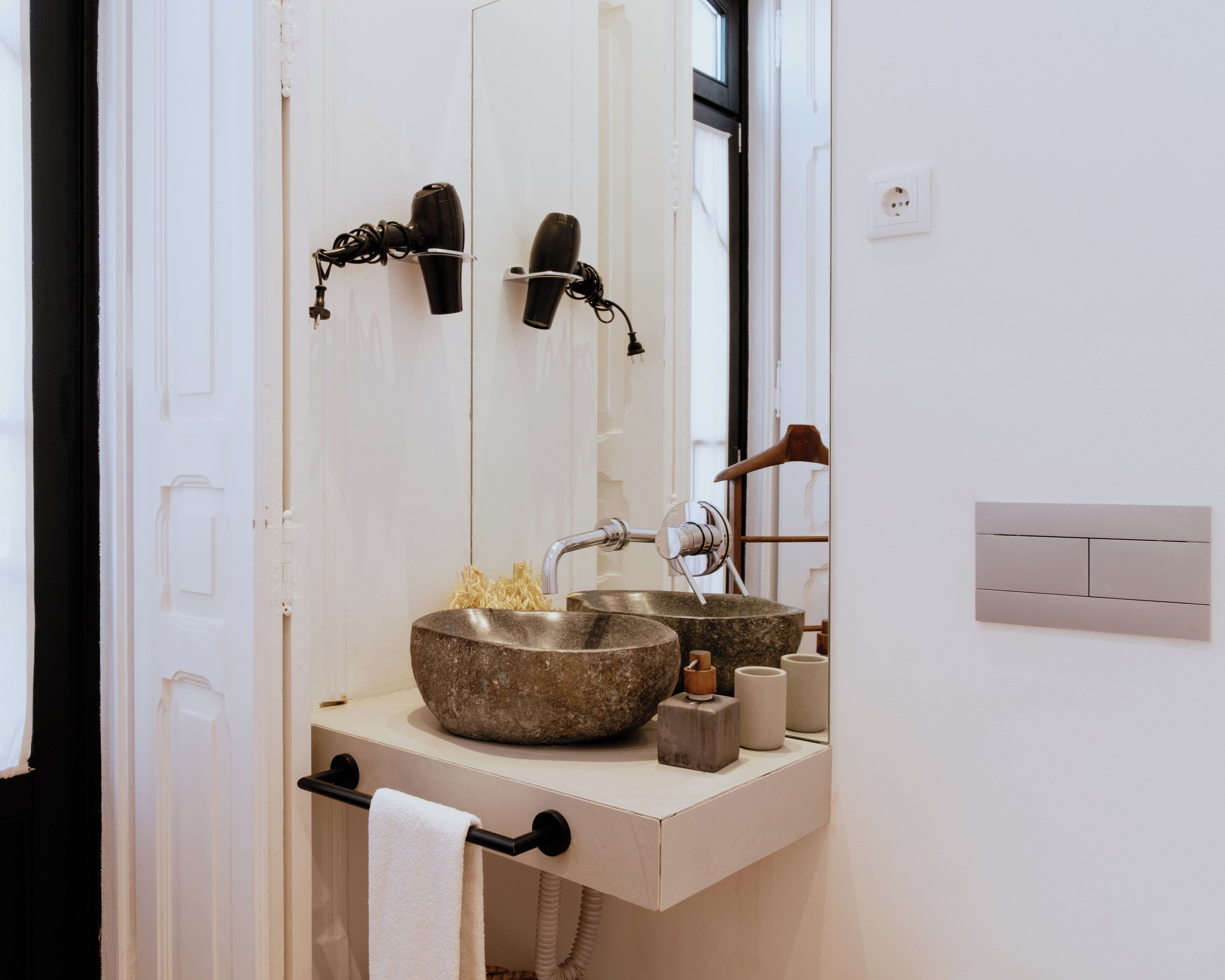A bathroom with a stone sink, a towel rack, and a mirror.